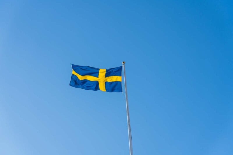 Flaggstång med Svenska flaggan mot en blå himmel.