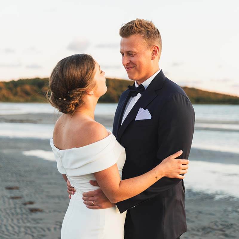 Bröllopsfoton på stranden i solnedgången.