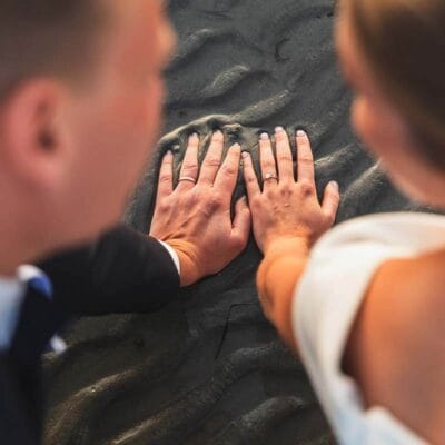 Bröllopsfoto i sanden. Bröllopsbild med ringarna i fokus. Vigselringar.