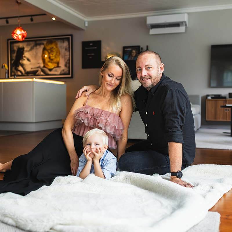 Familjefotografering hemma i vardagsrummet. Familjebilder på en mysig filt.